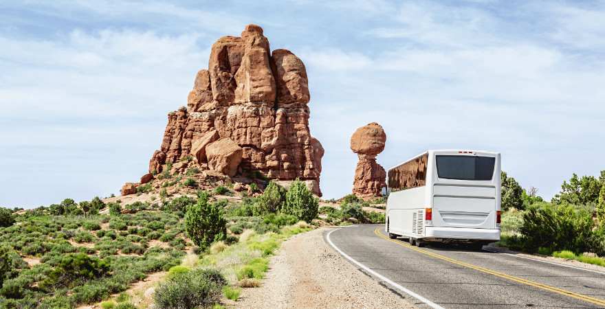 Ein Reisebus auf einer Straße vor roten Felsen