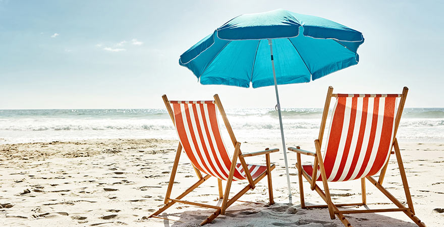Liegestühle unter Sonnenschirm am Strand